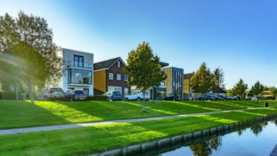 white and brown house near green grass field and body of water during daytime