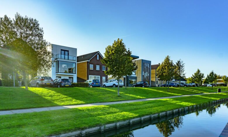 white and brown house near green grass field and body of water during daytime
