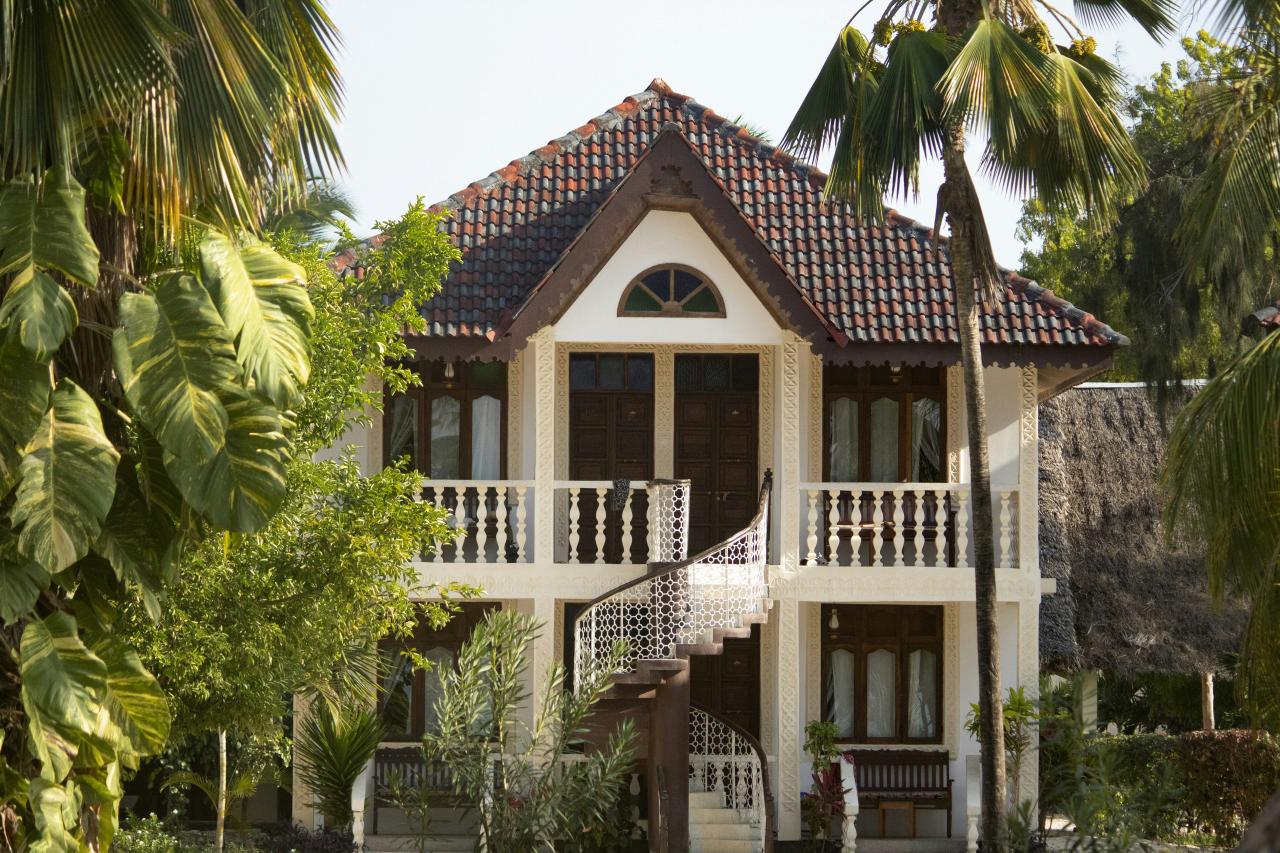 a white house with a brown roof surrounded by palm trees