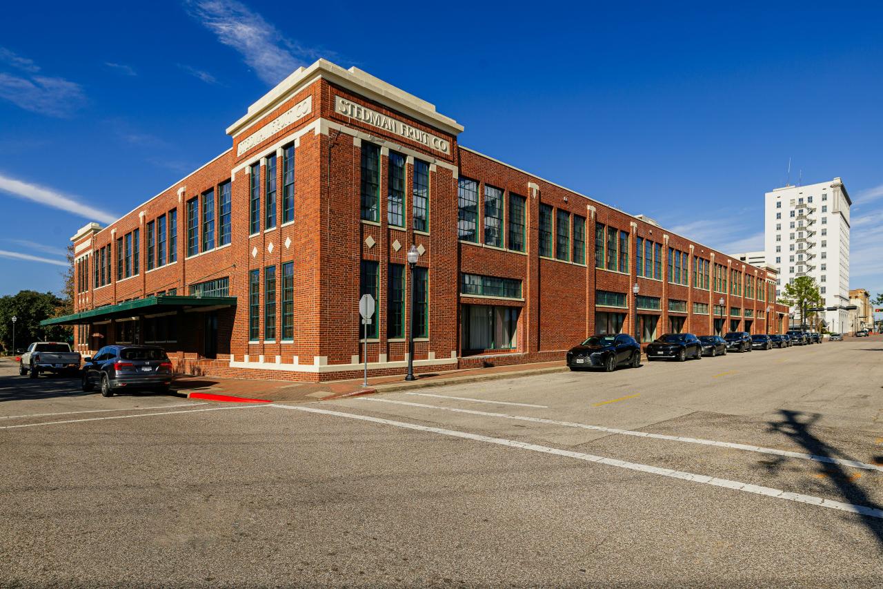 An empty parking lot in front of a large brick building